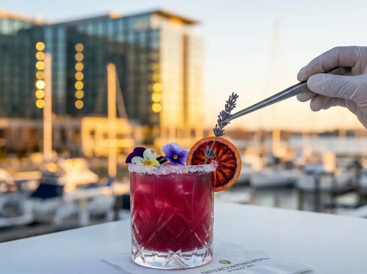 Close-up of a vibrant mocktail being garnished at a Wharf DC waterfront event, modern hotel architecture and city lights softly blurred behind